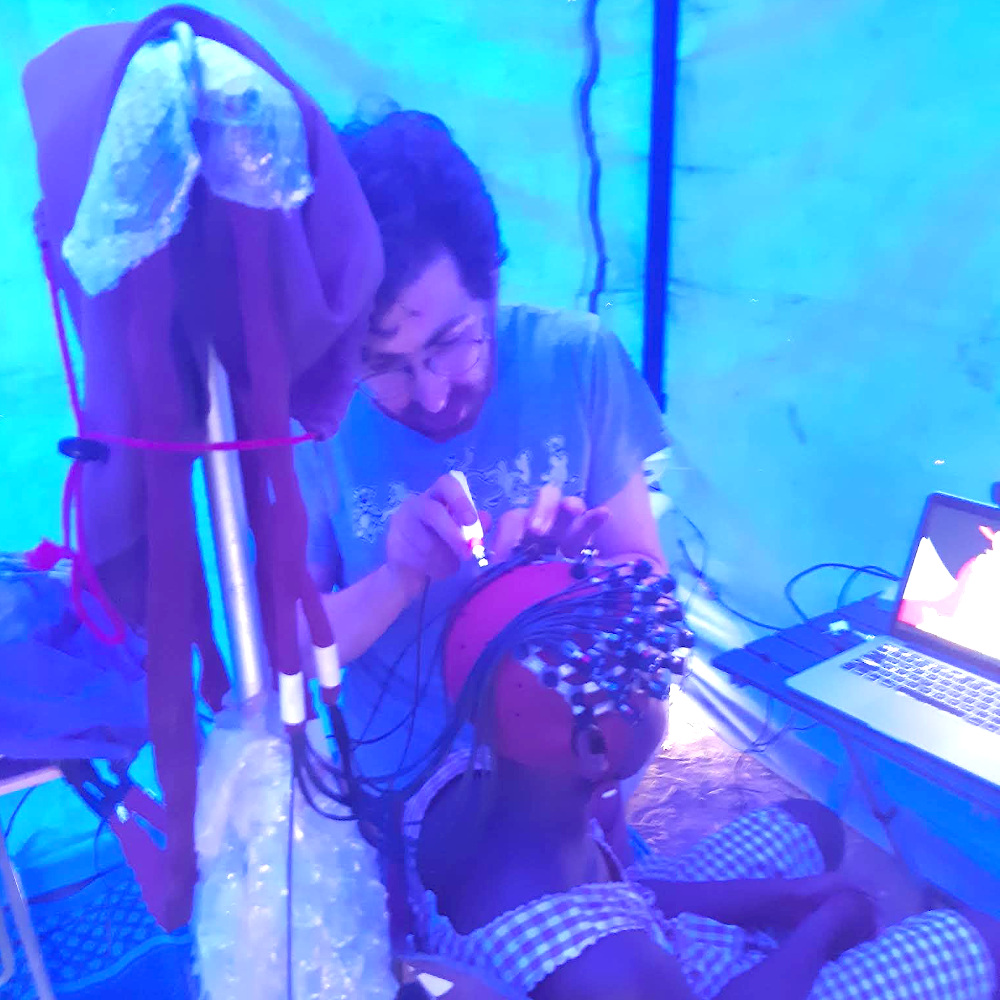 Ben doing fNIRS imaging in a blue tent at a primary school
